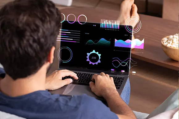 Mann, der einen Laptop benutzt, mit einem futuristischen holografischen Daten-Overlay, über seiner Schulter.