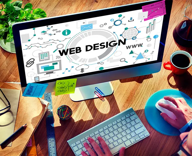 Eine Person, die an einem Computer arbeitet, auf dessen Bildschirm 'Web Design' und verschiedene Icons angezeigt werden. Der Schreibtisch ist mit Haftnotizen, einem Notizbuch und einer Tasse Kaffee bedeckt. Die Arbeit auf dem Bildschirm zeigt professionelles Webdesign.